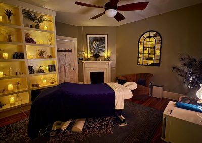 Massage table beside the arched mirror and candle wall